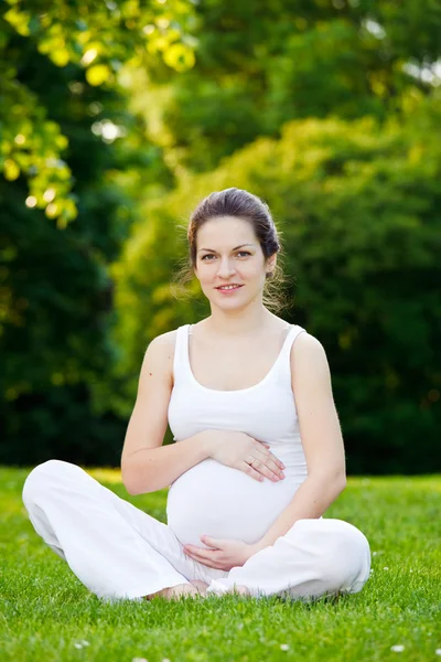 Mulher grávida bonita relaxante no parque — Fotografia de Stock