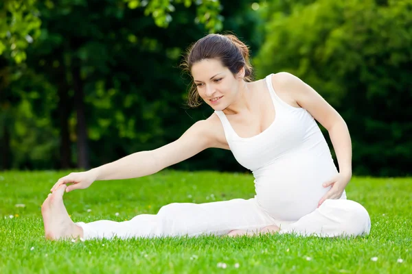 Mulher grávida bonita praticando no parque — Fotografia de Stock