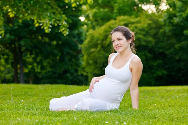 Krásná těhotná žena relaxuje v parku — Stock fotografie