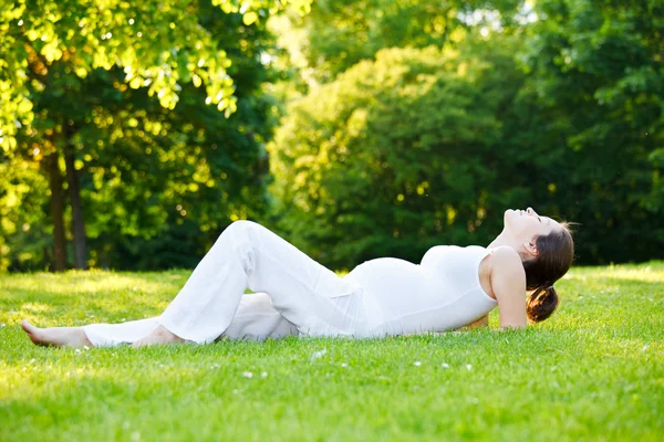 公園でリラックスした美しい妊婦 ロイヤリティフリーのストック写真