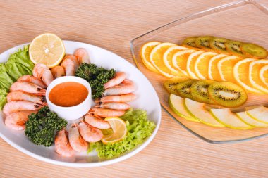 Shrimps and fruits on table clipart