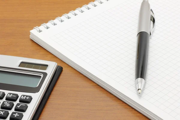Блокнот с ручкой и калькулятором — стоковое фото