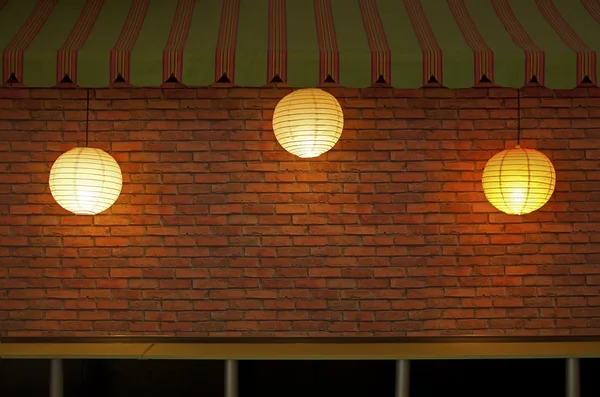 Bakstenen muur met drie verlichte lampen — Stockfoto