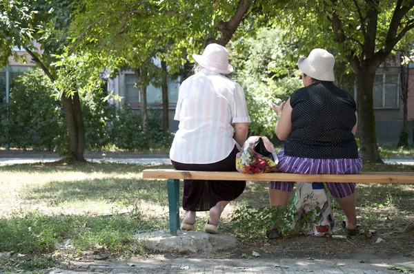 Две пожилые женщины, сидящие на скамейке — стоковое фото