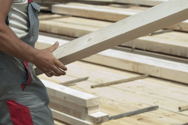 Εργαζόμενος κινείται ένα ξύλινο δοκάρι — Φωτογραφία Αρχείου