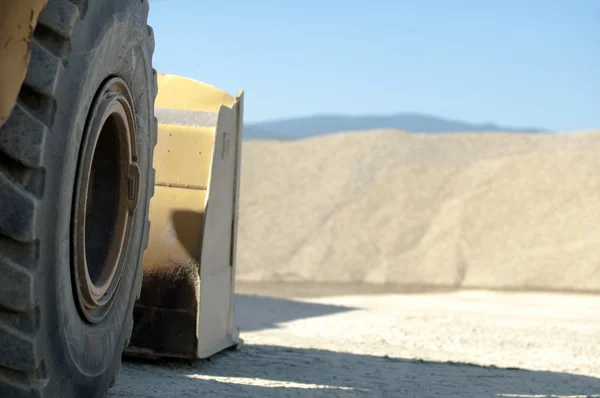 Däck traktorgrävare närbild och högar av sand — Stockfoto