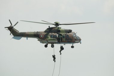 Two soldiers hanging from a helicopter clipart