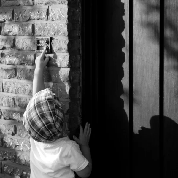 Ein kleiner Junge klingelt an der Tür lizenzfreie Stockfotos