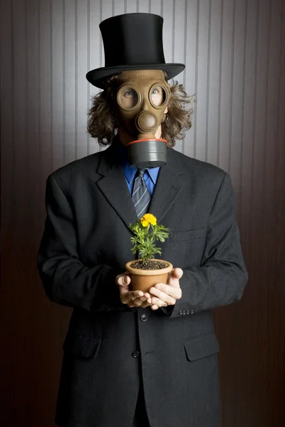 Mann med gassmaske som holder en blomst stockbilde