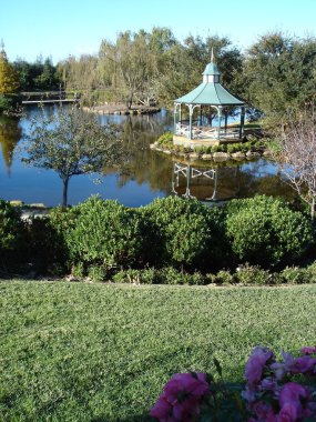 Formal hedges and gazebo near lake clipart