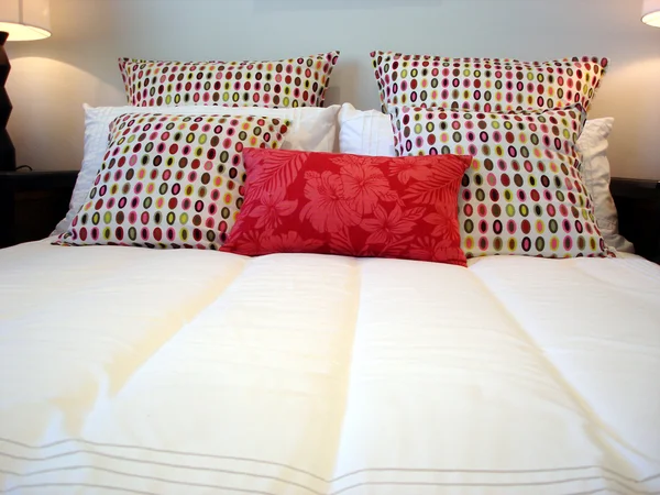 Witte slaapkamer met heldere roze kussens — Stockfoto