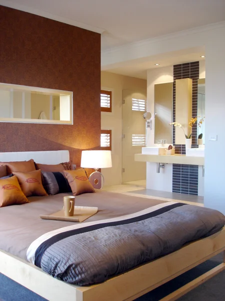 Moderne slaapkamer met warme tinten en ensuite badkamer — Stockfoto