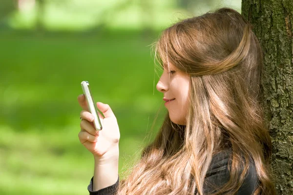 Aantrekkelijk meisje met telefoon in park — Stockfoto