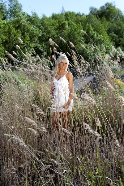 Dívka stojí v suché trávě — Stock fotografie