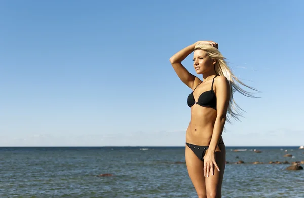 Dziewczyna w bikini pozowanie na skale w pobliżu morza — Zdjęcie stockowe