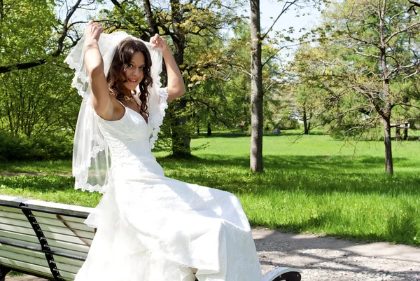 年轻貌美的新娘坐在公园的长椅上 — 图库照片