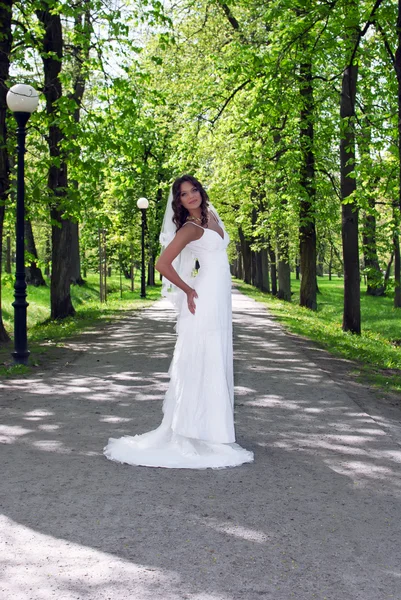 Jovem noiva de pé em um beco no parque — Fotografia de Stock