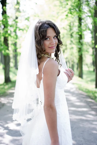 Giovane sposa in piedi in un vicolo nel parco — Foto Stock