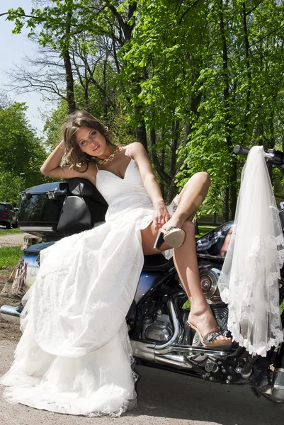 Mooie jonge bruid zittend op een motorfiets — Stockfoto