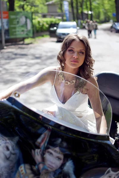 Schöne junge Braut sitzt auf einem Motorrad — Stockfoto