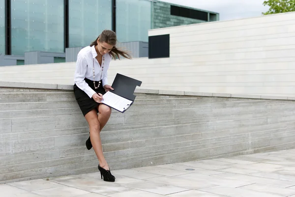 Mulher de negócios assinar documentos no fundo de um edifício de negócios — Fotografia de Stock
