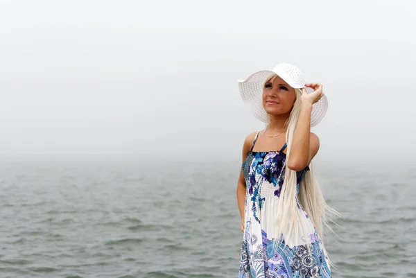 Mädchen mit Hut steht im nebligen Meer — Stockfoto