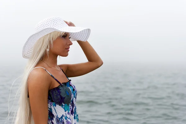 Flicka i hatt stående i det dimmiga havet — Stockfoto