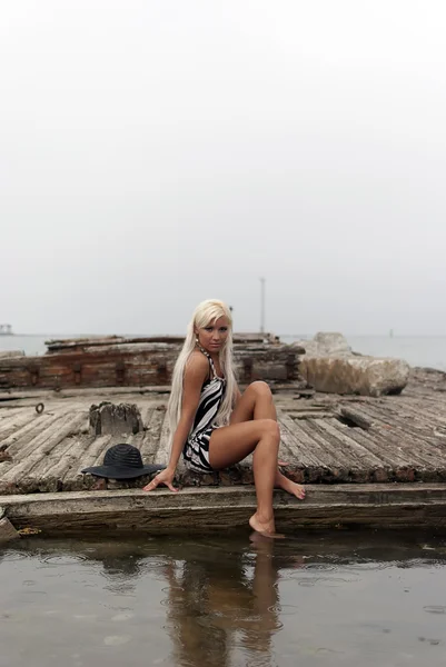 Mädchen mit Hut sitzt auf einem kaputten Schiff auf See — Stockfoto