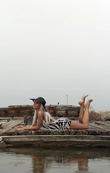 Lány a kalapban, ül egy törött hajó a tengeren — Stock Fotó