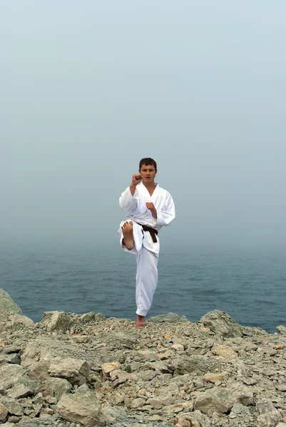 Karate trains on the shores of the misty sea — Stock Photo, Image