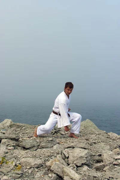 Karate trains on the shores of the misty sea — Stock Photo, Image
