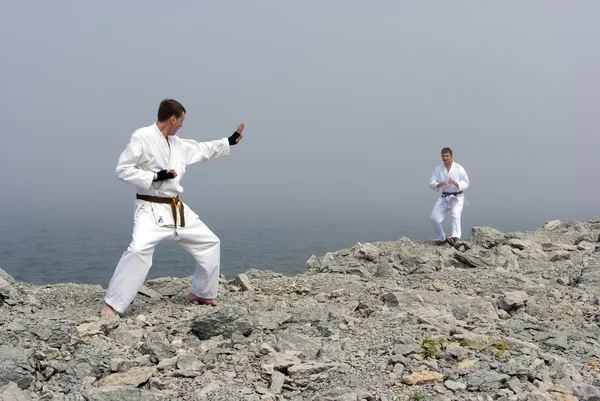 Zwei Karateka kämpfen am Ufer des nebligen Meeres — Stockfoto