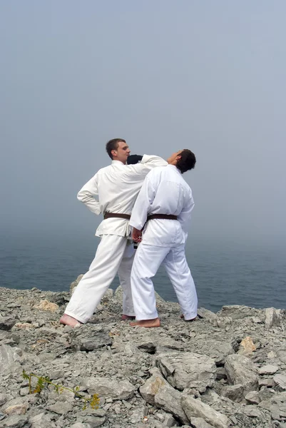 Två karateka kampen på packar ihop av det dimmiga havet — Stockfoto