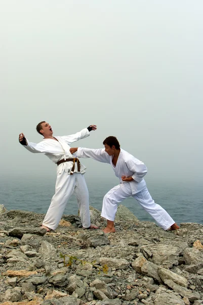 Two karateka fight on the banks of the misty sea — Stock Photo, Image