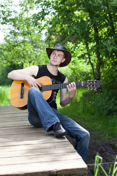 Mężczyzna gra na gitarze w lesie — Zdjęcie stockowe