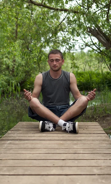 Uomo seduto nella posizione del loto e medita — Foto Stock