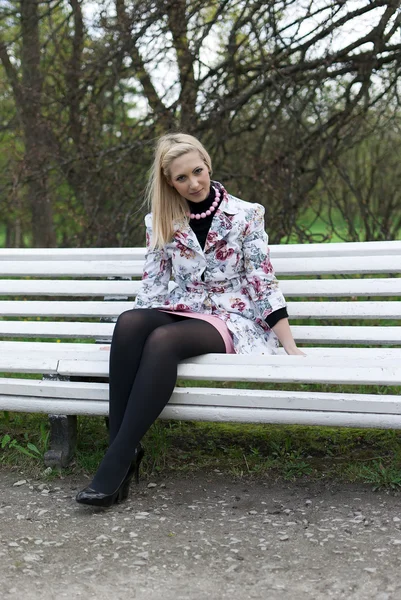 Blondes Mädchen sitzt auf einer Parkbank — Stockfoto