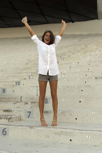 Mooi meisje springen in een leeg stadion — Stockfoto