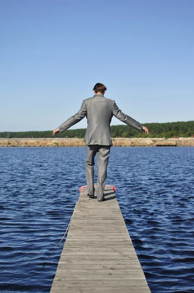 Man in a gray suit walking on the pier