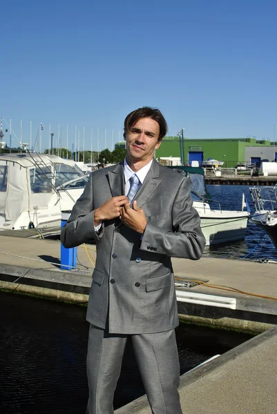 Чоловік у сірому діловому костюмі вирівнює краватку — стокове фото