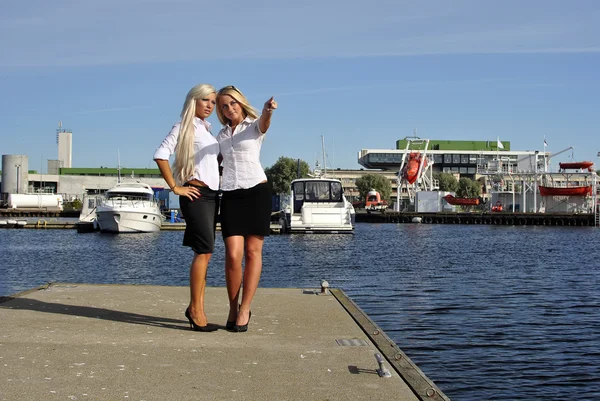 Zwei blonde Mädchen stehen auf der Seebrücke und zeigen mit dem Finger — Stockfoto