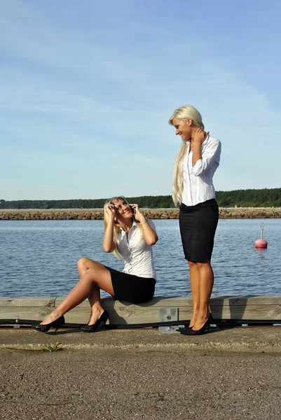 해변에서 두 여자입니다. 하나 서 있다. 또 앉아 있다 — 스톡 사진
