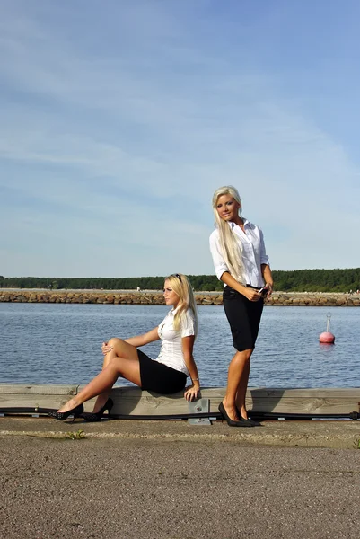 Två tjejer på stranden. en står. en annan sitter — Stockfoto