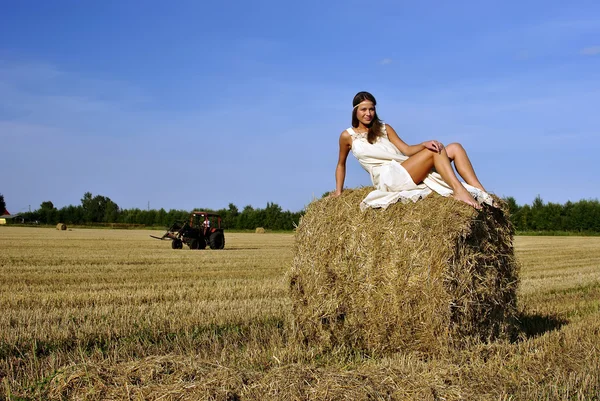 Dívka v venkovské oblečení sedí na kupce sena — ストック写真