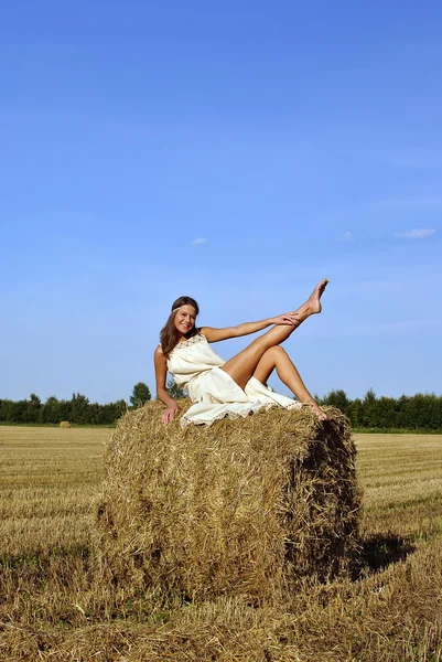 Meisje in een landelijke kleding zittend op de hooiberg — Stockfoto