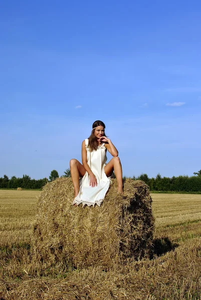 坐在草垛上农村服装的女孩 — 图库照片
