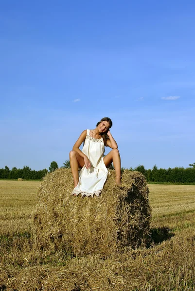 Lány a vidéki ruházati ül a szénakazalban — Stock Fotó
