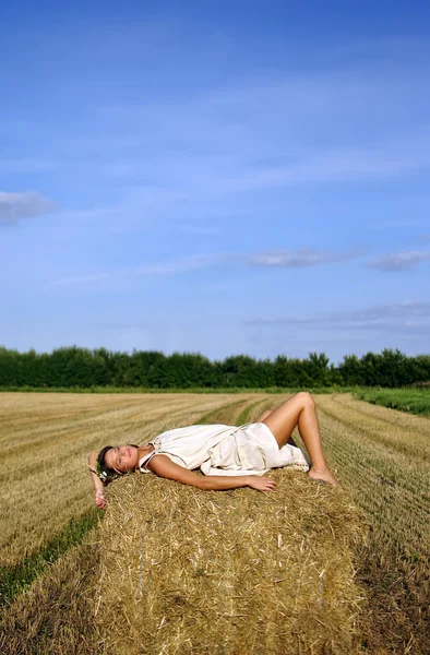 Dívka v venkovské oblečení ležící na kupce sena — Stock fotografie