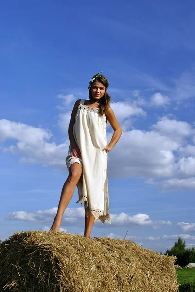 Flicka i en rural kläder står på höstacken — Stockfoto