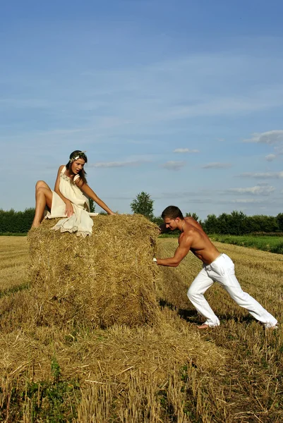 Bodybuilder pushes a haystack with a girl on top — Stock Photo, Image